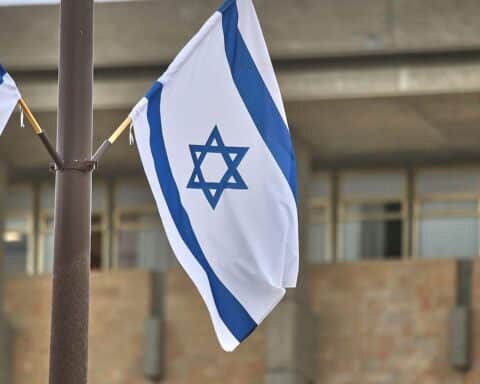 Israelische Flagge an der Knesset mit warnenden Sirenen und Militarisierung in der Luft.