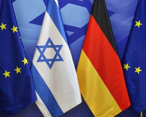 EU-, Israel- und Deutschlandfahnen symbolisieren den Schutz und die Zusammenarbeit im Verteidigungsbereich.