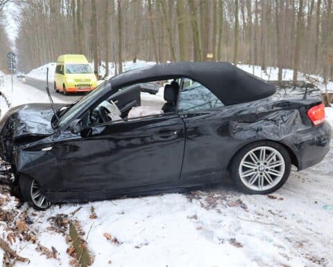 Ein Unfallauto prallt gegen Baum, schneebedeckte Straße, Polizei und Rettungswagen im Einsatz.