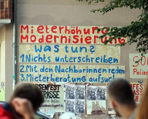 Mieter protestieren gegen hohe Mieten, Banner fordert faire Wohnpreise und Schutz vor Erhöhungen.