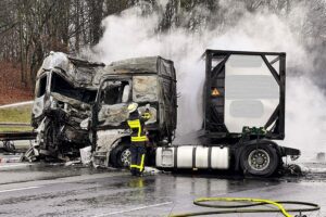 Zwei brennende LKWs auf der Autobahn, Feuerwehr im Einsatz, Unfallstelle mit Chaos.