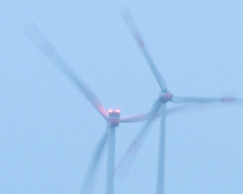 Windräder mit Anwohnern, die über finanzielle Beteiligung an erneuerbarer Energie diskutieren.