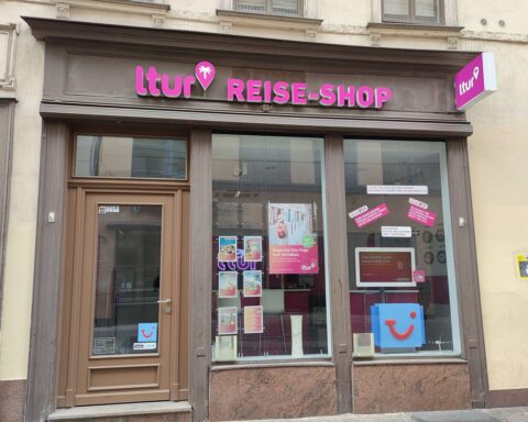 Reisebüro mit Angeboten für Budgetreisen, günstige Urlaubsziele, Kundeninteresse, Tui-Logo im Hintergrund.