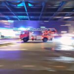 Feuerwehr-Einsatzwagen an Unfallstelle, Sichtschutz, Trauernde und Rettungskräfte bei Bergungsarbeiten.