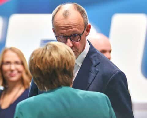 Friedrich Merz und Angela Merkel beim CDU-Parteitag, positive Atmosphäre, kameratische Interaktionen.