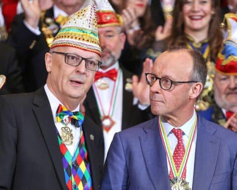 Bundeskanzler Merz empfängt fröhliche Karnevalisten im Kanzleramt, bunt geschmückt mit Kostümen.