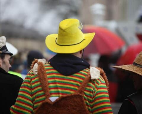 Ein Karnevalsmotiv mit bunten Kostümen und einer Warnung vor K.O.-Tropfen.