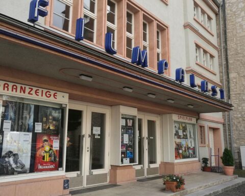 Kino-Szene mit Filmprojektionen und Menschen, symbolisiert die deutsche Filmförderung und Investitionen.