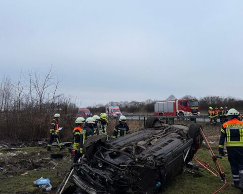 Ein verunfallter Audi A6 auf einer Wiese, umgeben von Einsatzkräften und Fahrzeugen.
