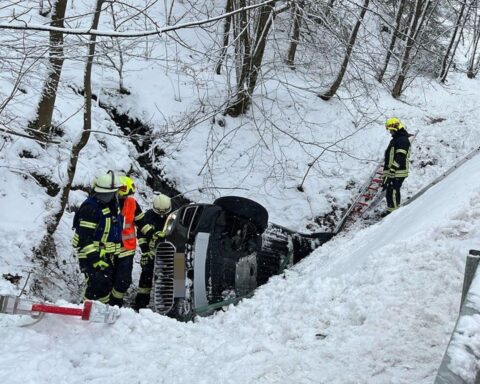 Rettungskräfte bergen Verletzte nach schwerem Unfall auf winterglatter Straße, BMW im Bachbett.
