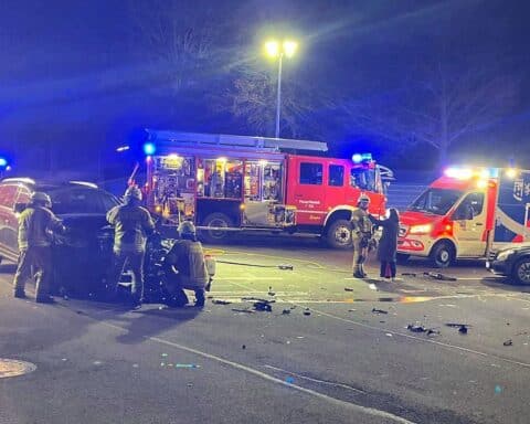 Verkehrsunfall mit zwei Autos, Rettungskräfte vor Ort, beschädigte Fahrzeuge auf der Straße.