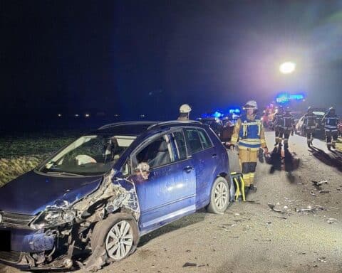 Zwei beschädigte Pkw nach Unfall, Feuerwehr im Einsatz, Verletzte werden versorgt.