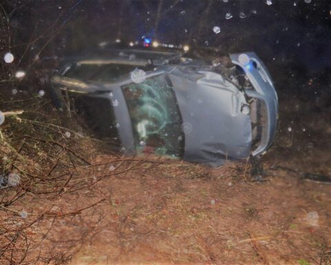 Ein umgekipptes Auto neben der Straße, umgeben von Vegetation und Unfallspuren.