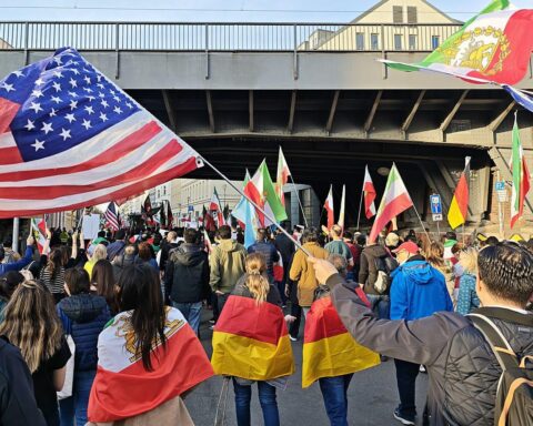 Demonstration in Berlin mit Flaggen, fröhlichen Menschen und Schildern für einen Regimewechsel im Iran.