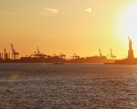 New Yorker Hafen mit Freiheitsstatue symbolisiert wirtschaftliche Herausforderungen und politische Entscheidungen in den USA.