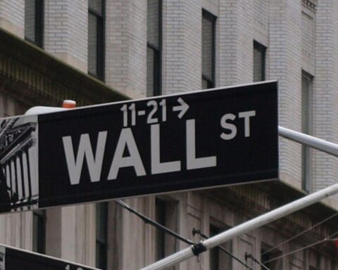 Blick auf die Wall Street mit Marktanalysen und Unternehmensergebnissen im Hintergrund.