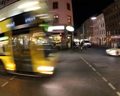 Nachtbus in Berlin mit Einschussloch in der Scheibe, Polizeiarbeit im Hintergrund.