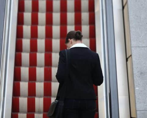 Frau auf Rolltreppe symbolisiert Arbeitsmarktungleichheit zwischen Männern und Frauen 2025.