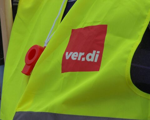 Menschen demonstrieren für faire Löhne im öffentlichen Dienst, Transparente und Banner sichtbar.