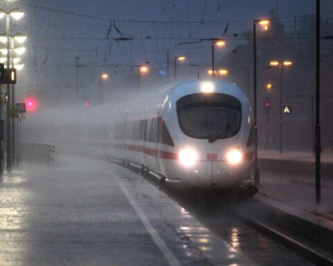 Ein ICE-Zug fährt bei starkem Regen und Wind durch eine ungemütliche, stürmische Landschaft.