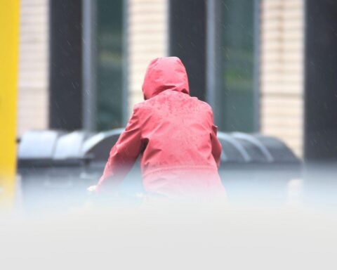 Mann mit Kapuze im Wetterwechsel, symbolisiert milde und kalte Temperaturen in Nordrhein-Westfalen.