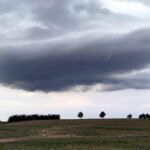 Dunkle Wolken über einem Acker, kündigen Regen und kühles Wetter an.