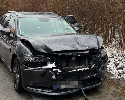 Zwei zerstörte Autos nach Verkehrsunfall, Polizei vor Ort, Verletzte werden ins Krankenhaus gebracht.
