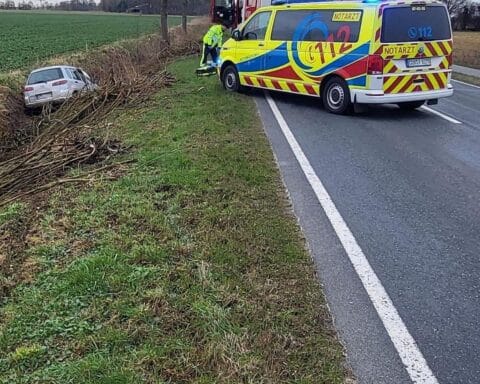 Unfallstelle mit gesichertem Fahrzeug, Polizei und Feuerwehr vor Ort, traurige Unfallnachricht.