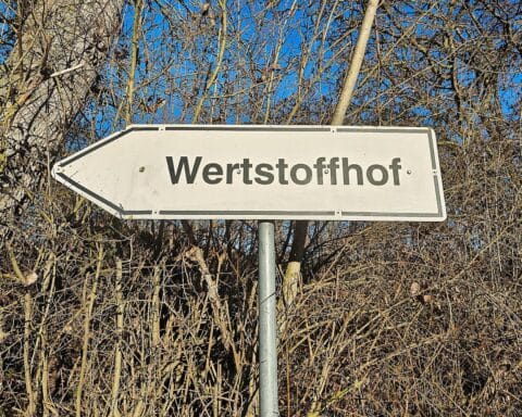 Wertstoffhof mit Abfallcontainern, der Rückgang der Deponiemengen in Nordrhein-Westfalen symbolisiert.