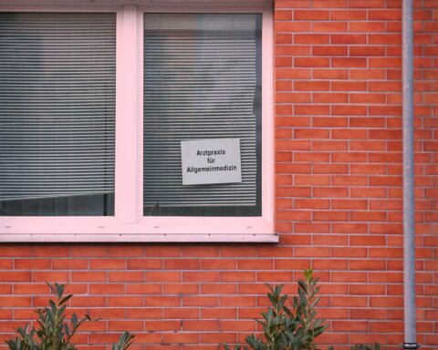 Arztpraxis mit Patient und Arzt im Gespräch über Krankmeldungen und Arbeitsunfähigkeitsregelungen.