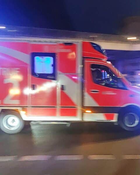 Ein Rettungswagen an einem Unfallort mit leicht verletzter Fahrerin und beschädigten Fahrzeugen.