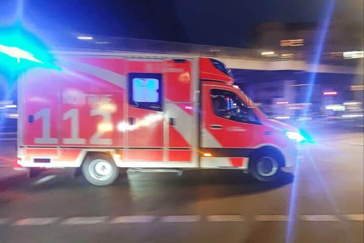 Ein Rettungswagen an einem Unfallort mit leicht verletzter Fahrerin und beschädigten Fahrzeugen.