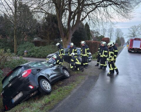 Unfallstelle mit Rettungskräften, Krankenwagen und eingesunkenem Auto im Seitengraben.
