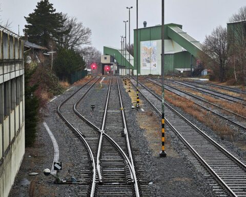 Gleise der Deutschen Bahn, umgeben von einem Stellwerk, symbolisieren den Personalmangel und Fortschritt.