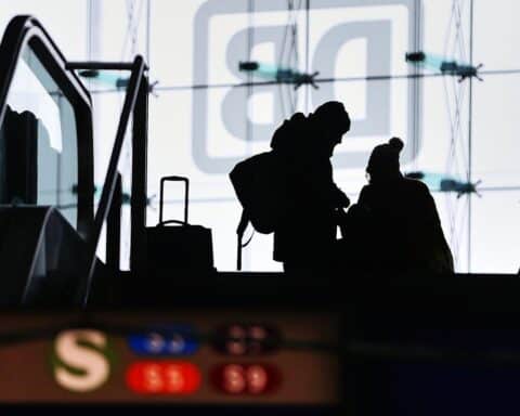 Reisende im Bahnhof, symbolisierende die wirtschaftliche Erholung und Herausforderungen der Deutschen Bahn 2025.