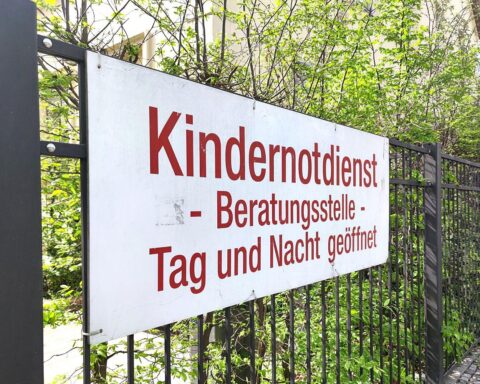 Ein Kind spielt fröhlich, während Betreuer im Hintergrund bei einer Jugendhilfe-Aktion helfen.