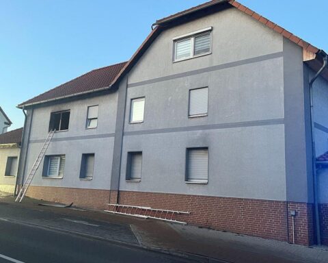 Brand in Mehrfamilienhaus, Rauch und Flammen sichtbar, Feuerwehr im Einsatz, Bewohner verletzt.