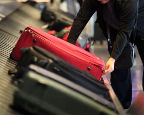 Deutsche Reisende am Gepäckband, im Hintergrund Sorgen um Rückreise aus Krisengebiet.