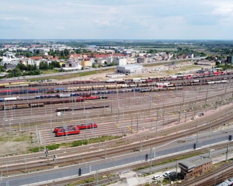 Zugbildungsanlage mit Güterzügen, DB Cargo-Logo, und eine wirtschaftliche Perspektive im Hintergrund.