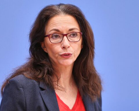 Yasmin Fahimi bei einer Rede über Sozialabbau und Arbeitsrechte, umgeben von kritischen Themen.