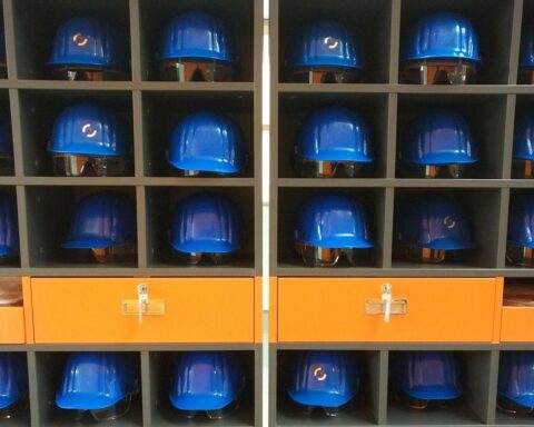 Grafik von Schutzhelmen, symbolisiert Diskussion über Arbeit und Feiertagsabschaffung zur Wirtschaftsanregung.