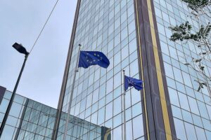 EU-Beamte kritisieren unpräzise Luftschläge im Iran EU-Fahnen vor Brüsseler Hintergrund, symbolisieren diplomatische Bemühungen um humanitäre Hilfe.