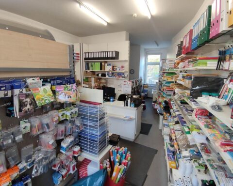 Büroartikelgeschäft mit Produkten, Umsatzstatistiken und Grafiken im Hintergrund, symbolisiert Einzelhandelstrends.