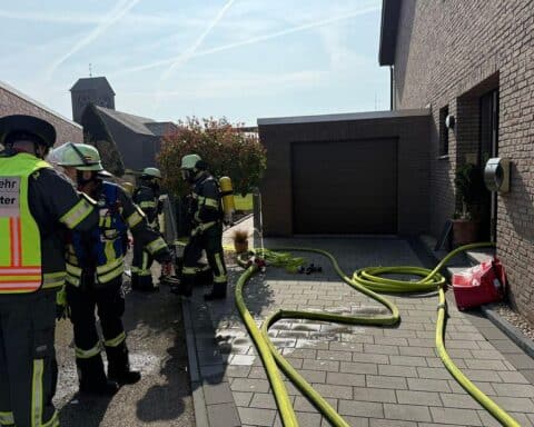 Rauch dringt aus Kellerfenster; Feuerwehr bei Brandbekämpfung in Reihenhaus in Werne-Horst.