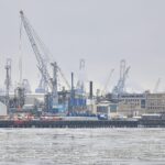 Ein Bild des Hamburger Hafens mit Containerschiffen und Euro-Symbolen für internationalen Handel.