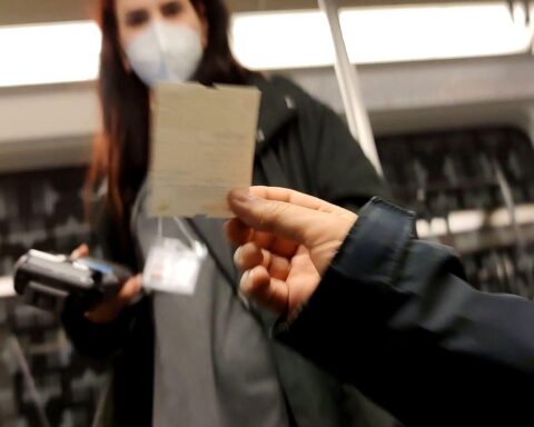 Fahrausweisprüfer kontrollieren Passagiere in einer S-Bahn, ein Konflikt entsteht. Polizist vor Ort.