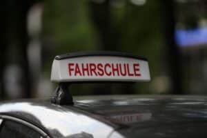 Fahrschule mit Lernenden, Prüfungen, Verkehrssicherheit in Diskussion, Bildung und Verantwortung betont.