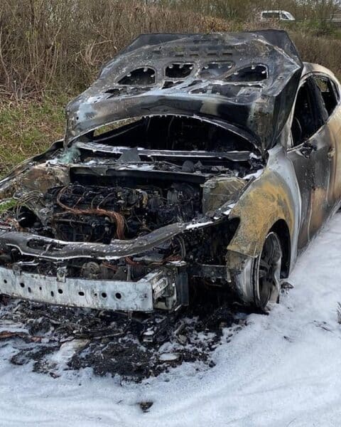 Ein ausgebrannter PKW auf der Autobahn, Feuerwehr im Einsatz, erhebliche Verkehrsbehinderungen.