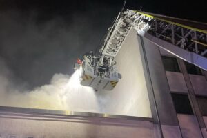 Feuerwehr löscht Brand mit Drehleiter in Dortmunds Innenstadt, liess Flammen am Dach sichtbar.