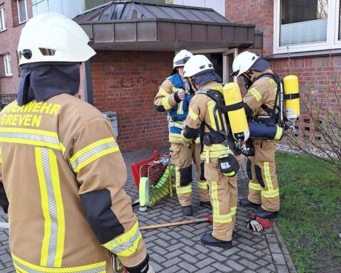 Feuerwehr löscht Brand in Kindergarten und Wohngebäude mit Atemschutz und Hochleistungslüftern.